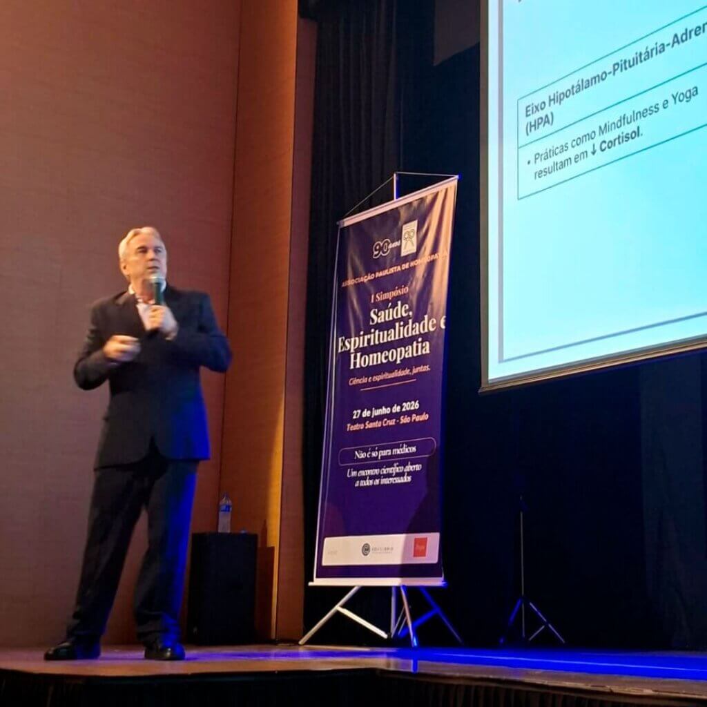 Dr. Marcus Zulian Teixeira durante sua palestra no simpósio, ao lado de slide sobre o eixo Hipotálamo-Pituitária-Adrenal e o cortisol.